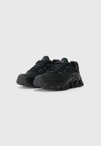 Des chaussures de sport noires avec une tige lisse, des détails texturés, une semelle épaisse et de multiples découpes offrent un rembourrage pour le confort et le soutien.