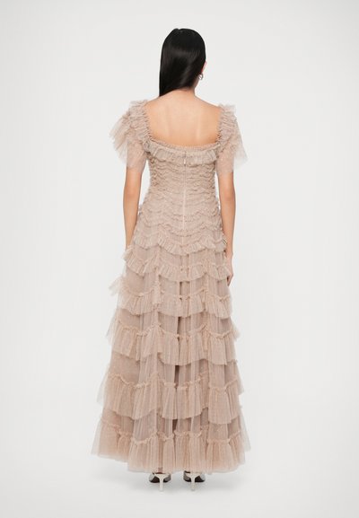 Pikk, kihiline kleit pehmest beežist tüllist, millel on volangilised aksessuaarid ja lühikesed pusa varrukad. Selja lukuga kinnitamine, põrandapikkune ning õrnade detailidega.