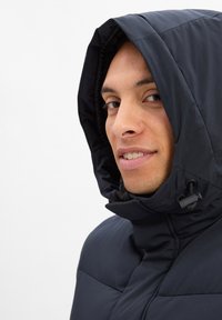 Ciemnoniebieska kurtka puchowa z kapturem. Teksturowany materiał, zapięcie na zamek błyskawiczny oraz regulowane sznurki przy szyi i kapturze.