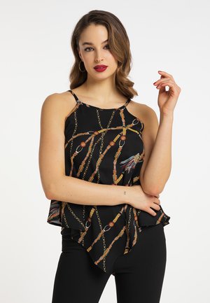 Giovane donna con capelli alla lunghezza delle spalle che indossa un top nero senza maniche con motivo a catena e cintura, posando con un braccio alzato.
