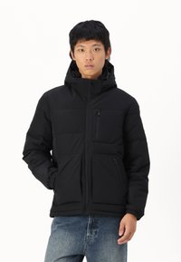 Chaqueta acolchada negra con capucha, cremallera frontal y bolsillos laterales. Cuenta con un bolsillo en el pecho con cremallera, diseñado para brindar calidez y comodidad.