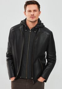 Veste en cuir noir au design élégant, avec une fermeture éclair à l'avant, un sweat à capuche gris en dessous, et des accents matériels minimaux.