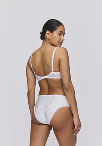 Set di lingerie bianca con motivo floreale sulla biancheria intima, delicate rifiniture in pizzo, spalline regolabili e una silhouette aderente.