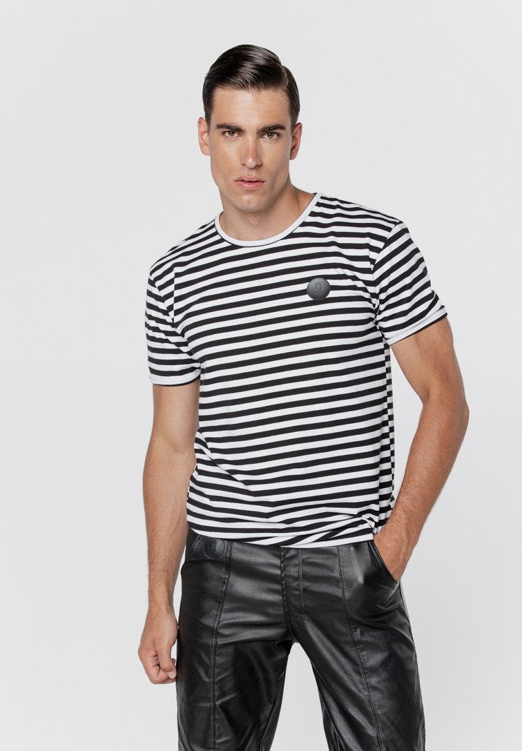 Czarna i biała koszulka w paski z okrągłym dekoltem, krótkimi rękawami i małym okrągłym logo na piersi. W połączeniu z eleganckimi czarnymi spodniami.