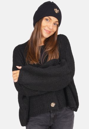 Schwarzer Strickpullover mit lockerer Passform, ausgestattet mit einem strukturierten Muster und einem herzförmigen Akzentknopf in Goldton am Saum. Schwarze Mütze inklusive.