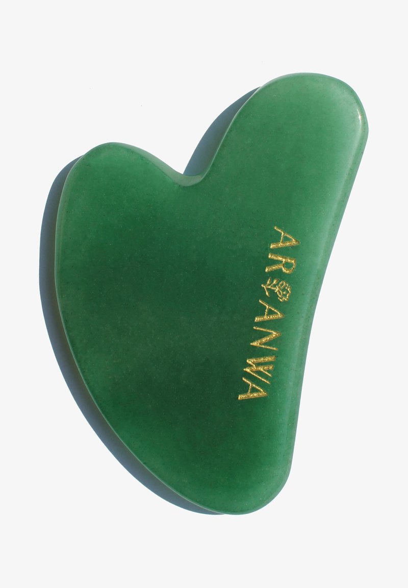 Green jade gua sha tool with a heart shape, smooth texture, and gold lettering. Slightly translucent with rounded edges.