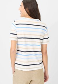 Stribet t-shirt i creme med lyseblå, mørkeblå og beige striber. Har en afslappet pasform med rund halsudskæring og korte ærmer.