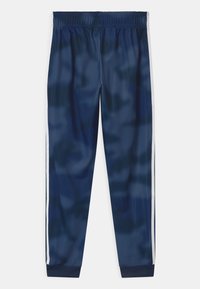 Tmavě modré sportovní kalhoty s elastickým pasem, bočními bílými pruhy a žebrovanými manžetami. Vyrobené z hladké, lehké látky.