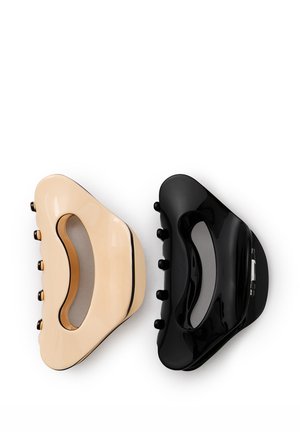 Deux pinces à cheveux en plastique brillant, une beige et une noire, placées côte à côte sur un fond blanc.