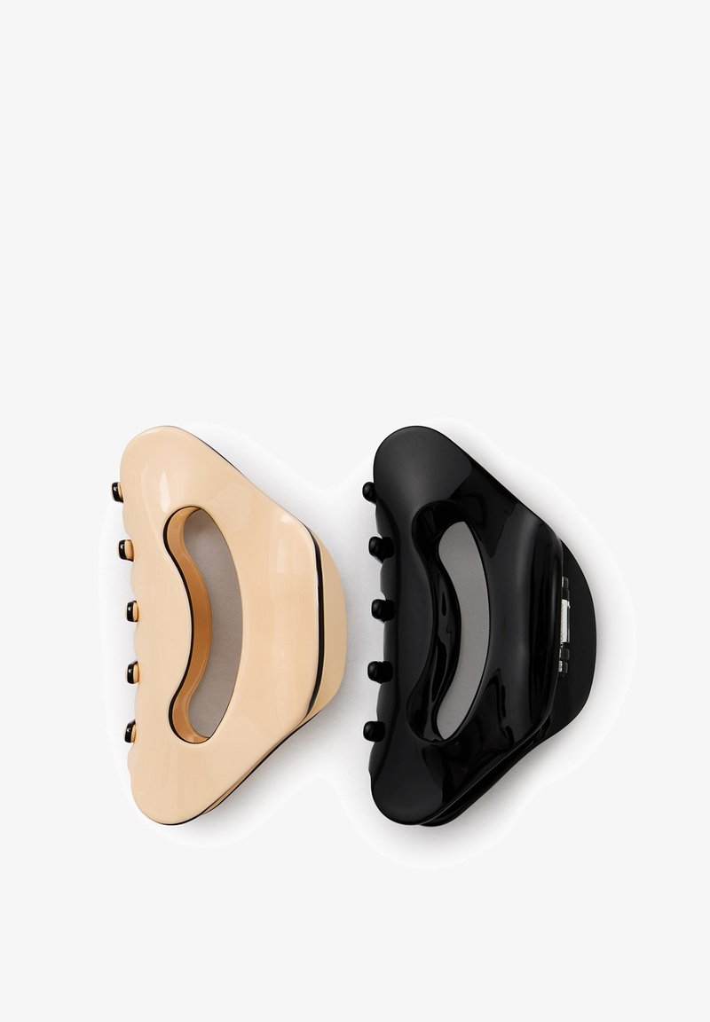 Two glossy plastic hair claw clips, one beige and one black, placed side by side on a white background.