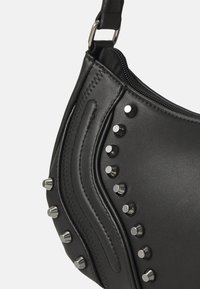 Black leather handbag with a curved shape, featuring silver studs along the seam, zip closure, and a detachable shoulder strap.