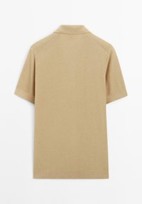 Polo a maniche corte di un leggero color beige, caratterizzato da un motivo a maglia testurizzata, colletto a coste e orlo pulito alle maniche.