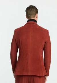 Rostfarbener Cordblazer mit gerippter Textur, Reverskragen und Knopfmanschetten. Die Rückansicht zeigt eine taillierte Passform und einen Sch vent.