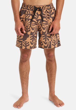 Bruine zwemshorts met een tropisch bladdessin in tan, voorzien van een elastische tailleband en een verstelbaar zwart trekkoord. Zwarte logo-details aanwezig.