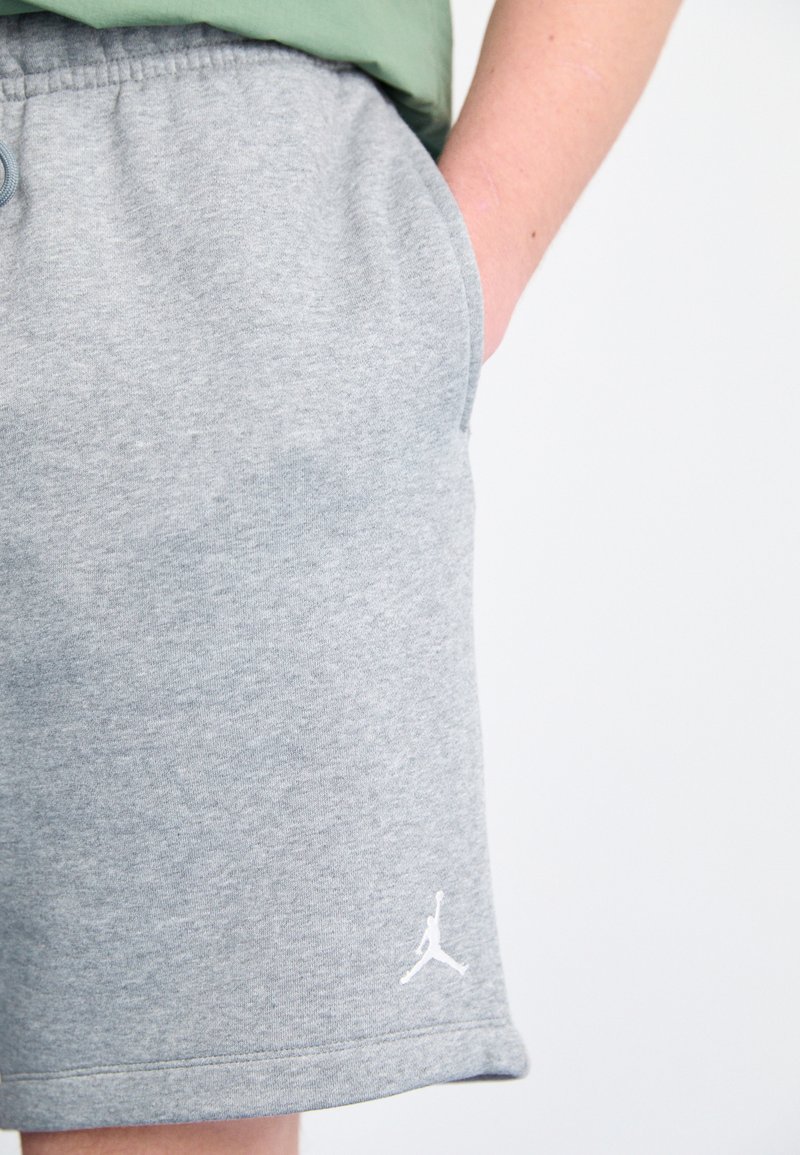 Pantalones cortos de mezcla de algodón gris con cinturilla elástica, bolsillos laterales y un acento de logo blanco en el dobladillo. Textura suave, corte que llega a la rodilla.