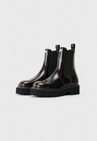 Hnedé lesklé kožené Chelsea boots s čiernymi elastickými bočnými panelmi, robustnými gumovými podrážkami a striebornými kovovými detailmi na päte.