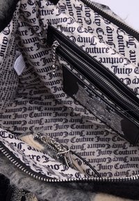 Interno della borsa testurizzato in nero e grigio con fodera stampata con logo, scomparti con zip e dettagli in hardware argentato.