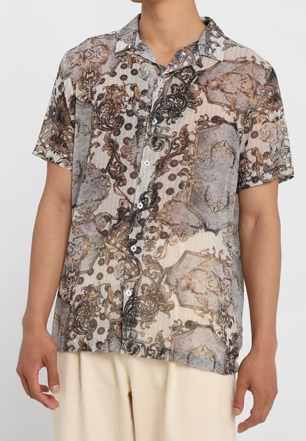 Camicia a maniche corte in beige e marrone, caratterizzata da intricati motivi barocchi, con chiusura a bottoni e una vestibilità rilassata con colletto a camicia.