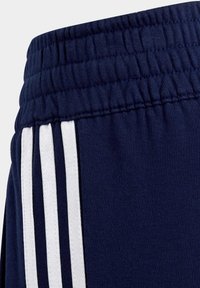 Marine sportshorts hebben een textuurstof, een elastische tailleband en witte gestreepte accenten aan de zijkanten.