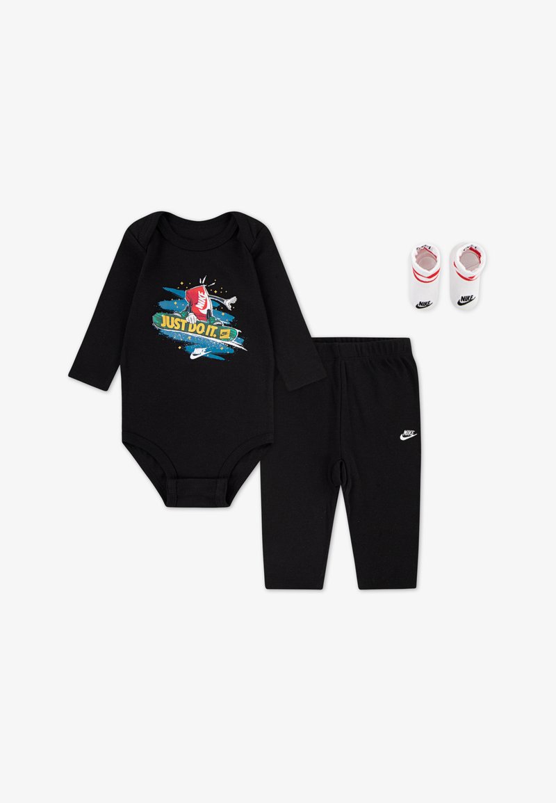 Svart långärmad bodysuit med "Just Do It" grafik, matchande svarta byxor och vita stövlar med röda detaljer och Nike-logotyper.