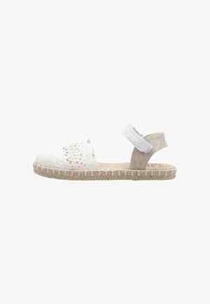 Sandale espadrille blanche arborant un motif en dentelle finement tissé, bride arrière en tissu beige et semelle enveloppée de jute.