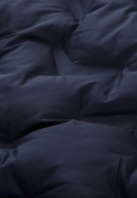 Mörkblå quiltad tyg med mjuka, vadderade sektioner och synliga sömmar som skapar ett tuftat mönster.