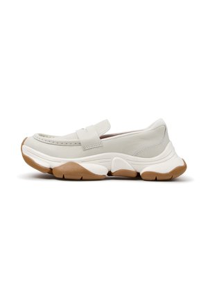Chaussure slip-on gris clair avec semelle en caoutchouc épaisse blanche et marron, coutures style mocassin et large bride sur le dessus.