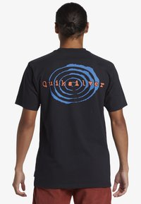 Black short-sleeve t-shirt featuring a circular blue graphic and "Quiksilver" in orange text on the back. Made of cotton.