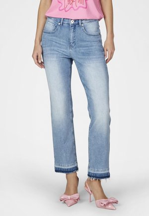 Woman wearing light blue cropped jeans with frayed hems and two-tone cuffs, paired with pink high-heeled shoes featuring large bows.
