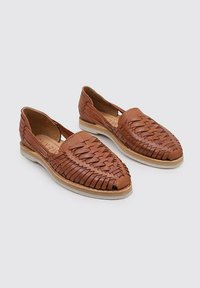 Zapatos de piel marrón con diseño superior tejido, punta afilada y suela de goma delgada. Cuenta con detalles texturizados y un perfil bajo.