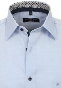 Lichtblauw button-up shirt met een comfortabele pasvorm. Opvallende donkere knoopdetails en een gepatenteerde kraagvoering. Voorzien van een borstzak.