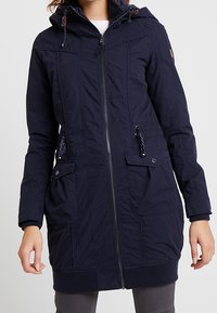 Granatowy długi płaszcz parka z zamkiem błyskawicznym, dwoma przednimi kieszeniami, regulowanym kapturem i detalami ze sznurkiem. Wykonany z teksturowanego materiału.