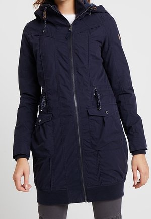 Parka larga de color azul marino con cremallera, dos bolsillos frontales, capucha ajustable y detalles de cordón. Fabricada en material texturizado.