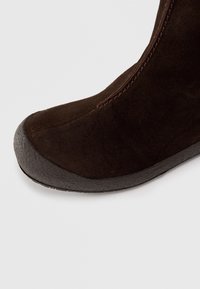 Brune semsket ankelstøvel med rund tå, strukturert gummisåle og kontrastfarget brun søm langs sømmen.