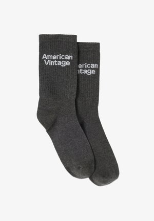 Hallid hallid sokid valge "American Vintage" tekstiga. Puuvilla segu materjal, keskpuusa pikkus ja sile tekstuur minimaalsete detailidega.