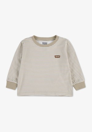 Chemise à manches longues à rayures horizontales beige et blanches, avec col et poignets beiges, et un petit écusson marron Levi’s sur la poitrine.