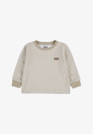 Chemise à manches longues à rayures horizontales beige et blanches, avec col et poignets beiges, et un petit écusson marron Levi’s sur la poitrine.