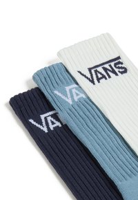 Tres pares de calcetines acanalados en azul marino, azul claro y blanco, cada uno con un destacado logo blanco de "VANS" en el puño. Textura de punto suave.