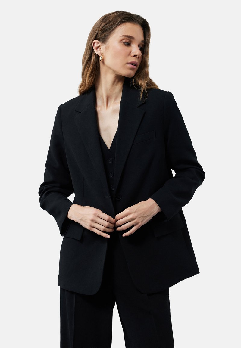 Zwarte op maat gemaakte blazer met een enkele zak, notch revers en een relaxte pasvorm, gemaakt van een soepele stof met een subtiele textuur.