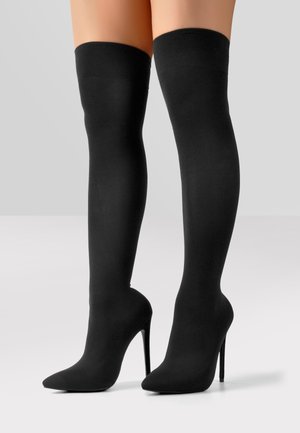 Bottes noires hautes jusqu'au genou à talon aiguille avec un bout pointu, en tissu lisse, et un talon fin.