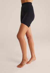 Augsti jostas melnie riteņbraukšanas šorti, kas izgatavoti no elastīga auduma, piedāvā gludu tekstūru, pieguļošu dizainu un vidēja garuma bikses līdz vidum augšstilba.