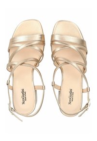 Metallic gold high-heeled sandals with crisscross straps, square toe shape, ankle buckle, and branded insole. Smooth texture throughout.