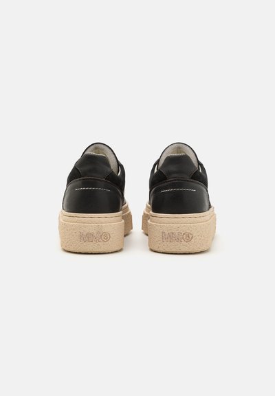 Svart läder sneakers med en klumpig beige sula. Har sömnadsdetaljer och en slät yta, med logotypen präglad på hälen.