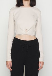 Beige ribbad långärmad crop top med en framugnippning, kombinerad med svarta sweatpants med dragsko.