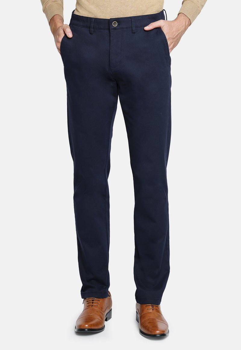 Chinos navy de mezcla de algodón, con cierre de botón, bolsillos delanteros y diseño de pierna recta, combinados con zapatos de cuero marrón.