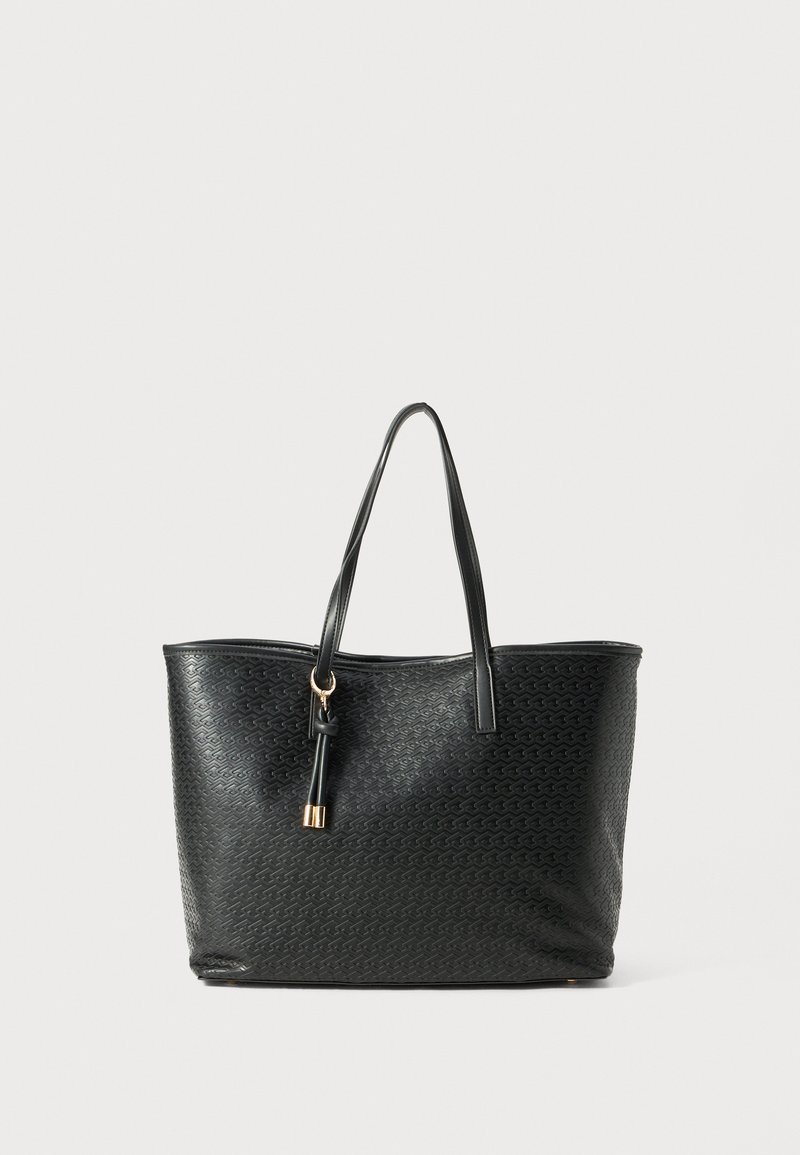 Black textured tote bag with long handles and a decorative tassel hanging from one handle against a plain light background.