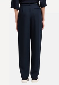 Pantalones de pierna ancha en color navy, confeccionados en una tela suave, con una cintura alta y un bolsillo trasero, acabados con detalles de costura mínimos.