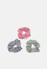 Três scrunchies de tecido xadrez: vermelho e branco, preto e branco, verde e branco. Cada um tem uma textura de tecido macio e um design elástico para o cabelo.