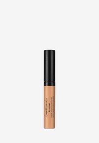 Correcteur liquide minéral dans un tube haut et élancé avec un capuchon noir mat et un corps beige comportant la marque et les détails du produit.
