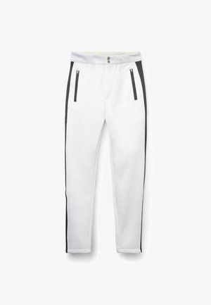 I pantaloni da atletica bianchi presentano strisce laterali nere, tasche con zip, chiusura con bottone e un design a gamba affusolata. Tessuto dalla texture liscia.